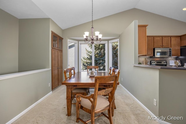 dining space featuring an inviting chandelier, lofted ceiling, light colored carpet, and baseboards