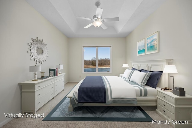 bedroom featuring a tray ceiling, light carpet, baseboards, and ceiling fan