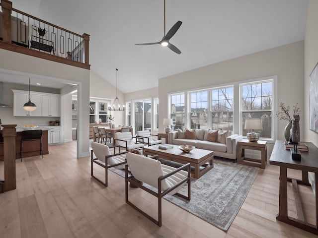 living room featuring ceiling fan with notable chandelier, a towering ceiling, and light wood finished floors