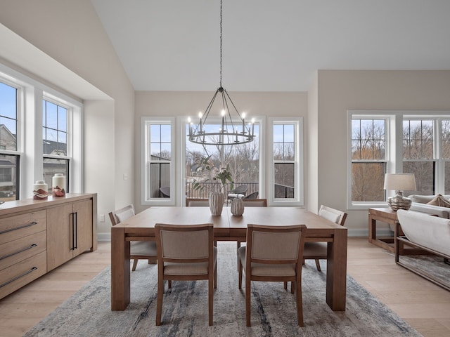 dining area featuring vaulted ceiling, light wood-style flooring, baseboards, and a chandelier