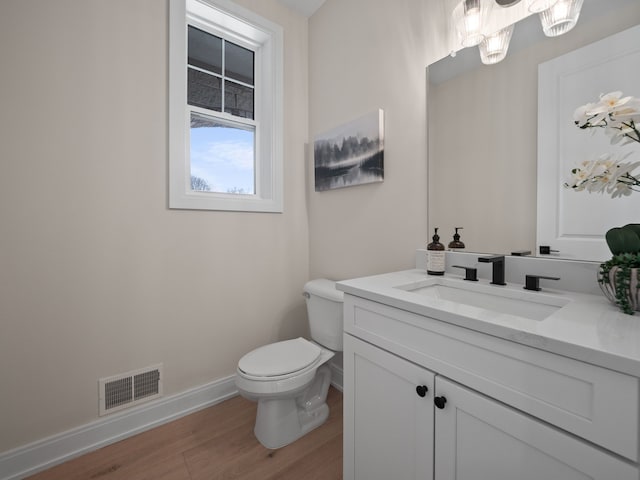 bathroom featuring vanity, wood finished floors, visible vents, baseboards, and toilet