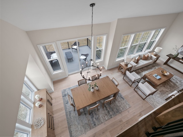 living room with an inviting chandelier, plenty of natural light, light wood-style floors, and baseboards