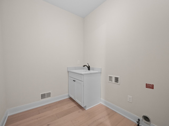 laundry room featuring visible vents, baseboards, light wood-style flooring, hookup for a washing machine, and a sink