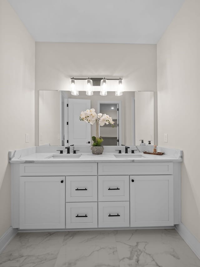 bathroom featuring a sink, marble finish floor, and double vanity