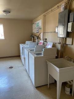 shared laundry area featuring electric panel, baseboards, independent washer and dryer, and a sink