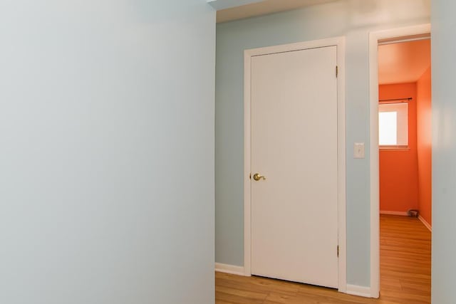 corridor with light wood-type flooring and baseboards