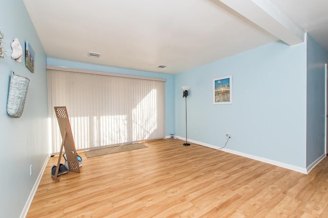 spare room featuring wood finished floors, visible vents, and baseboards