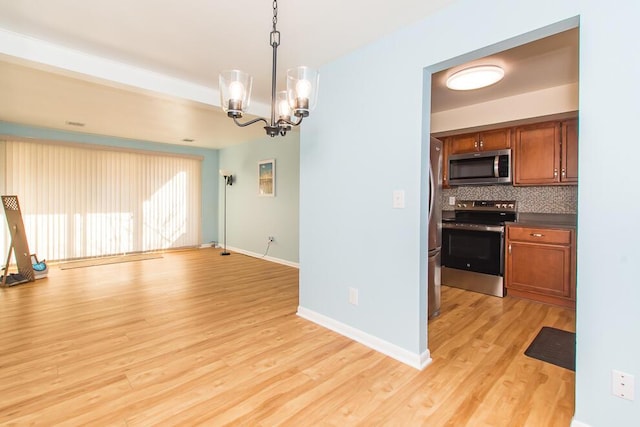 kitchen featuring stainless steel appliances, brown cabinets, decorative backsplash, and light wood finished floors