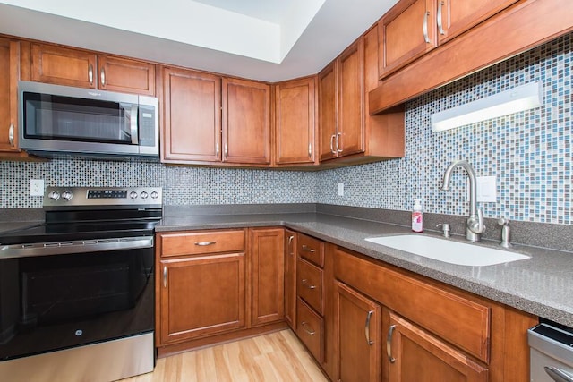 kitchen with brown cabinetry, stainless steel appliances, and a sink