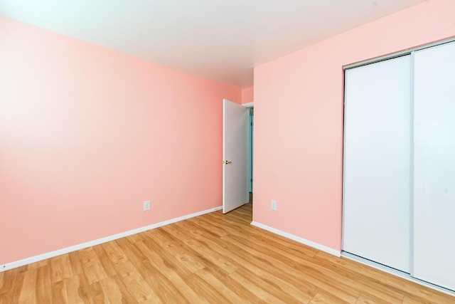 unfurnished bedroom with light wood-style floors, baseboards, and a closet