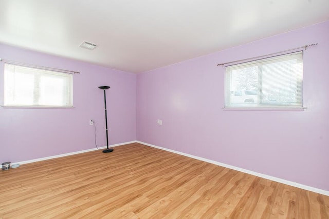 empty room featuring light wood-type flooring, visible vents, and a healthy amount of sunlight