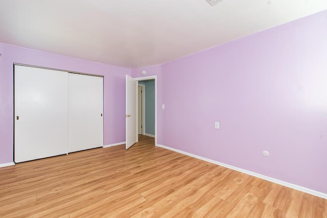 unfurnished bedroom featuring a closet, baseboards, and light wood-style floors