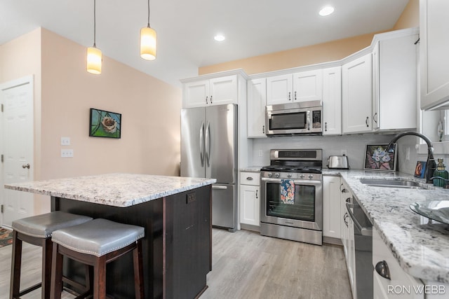 kitchen featuring a kitchen bar, decorative backsplash, appliances with stainless steel finishes, white cabinetry, and a sink