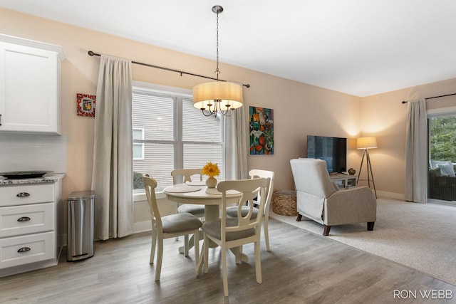 dining space with a notable chandelier, light wood-style flooring, and baseboards