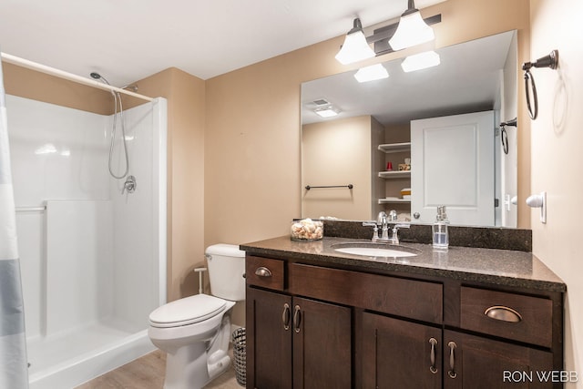 bathroom featuring vanity, a shower stall, toilet, and wood finished floors