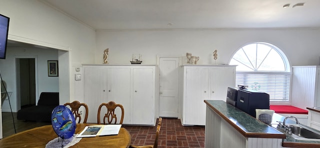 home office with crown molding, brick floor, and a sink