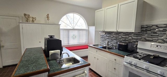 kitchen with dark countertops, gas range gas stove, tasteful backsplash, and a sink