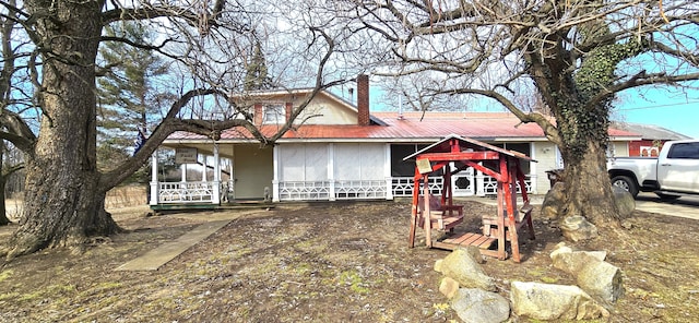 view of front of home featuring a porch, a chimney, and metal roof