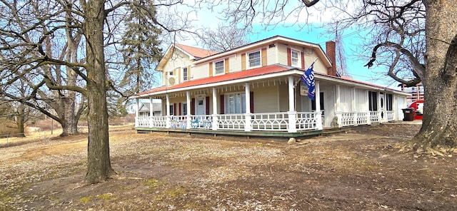 farmhouse with a porch, a chimney, and metal roof