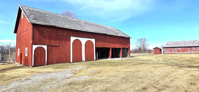 view of barn featuring fence and a lawn