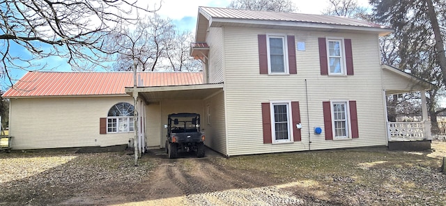 exterior space with a carport, dirt driveway, and metal roof