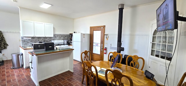 dining area featuring a wainscoted wall and brick floor