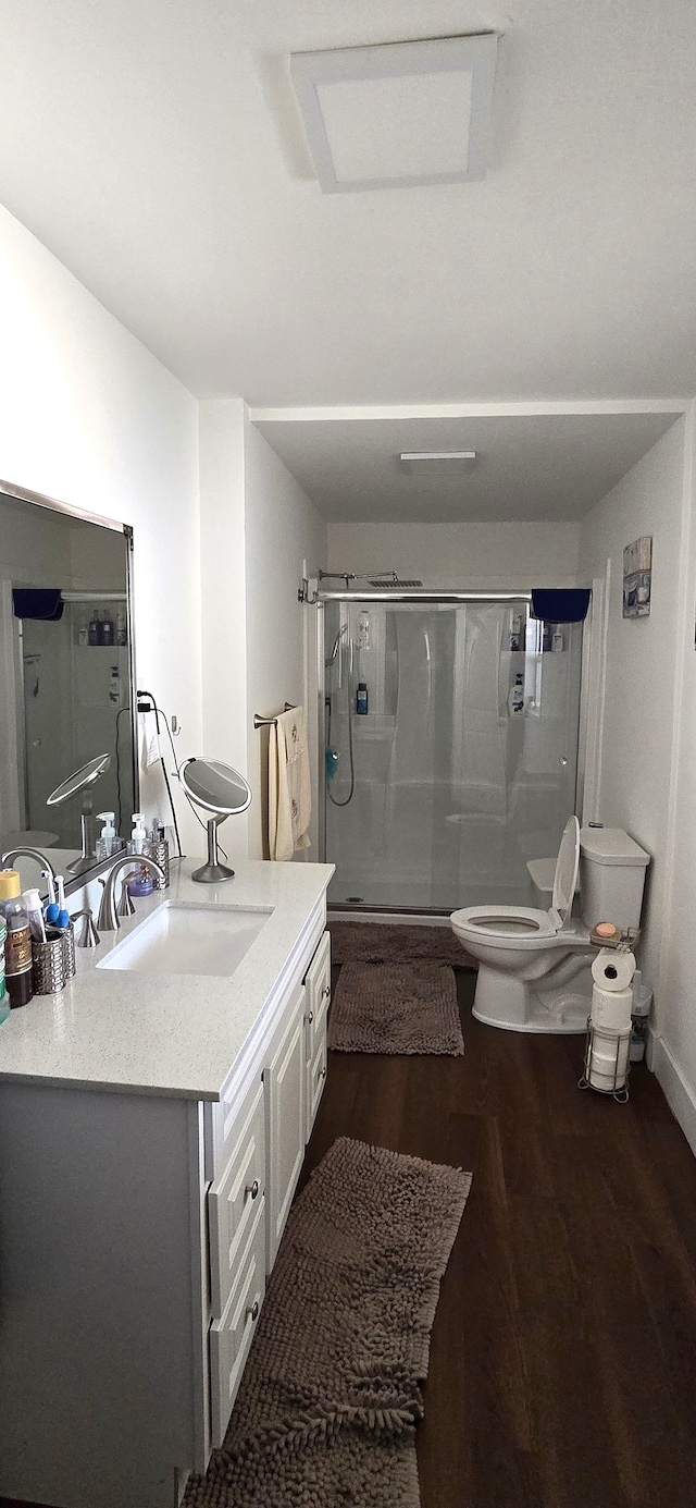 bathroom with a shower stall, vanity, toilet, and wood finished floors