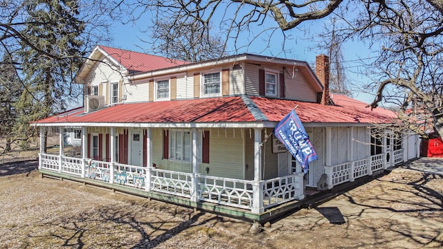 view of front facade with metal roof, a porch, and a chimney