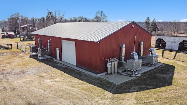 view of pole building with central air condition unit, a lawn, and fence