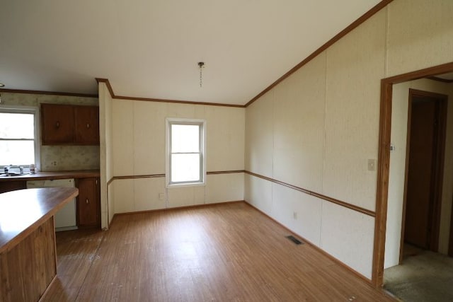 kitchen with dishwashing machine, visible vents, light wood finished floors, a sink, and ornamental molding