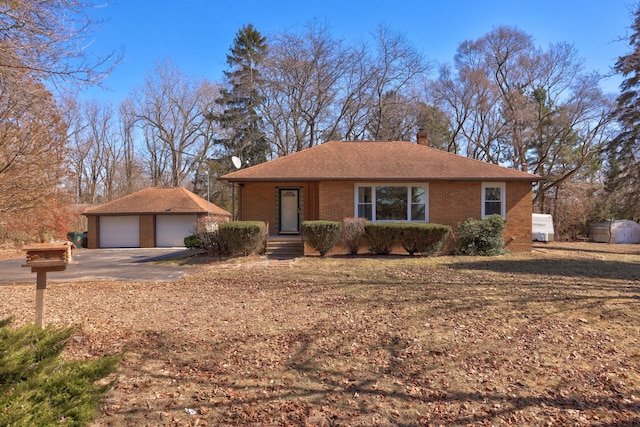 view of front of house with an outbuilding, brick siding, a garage, and roof with shingles