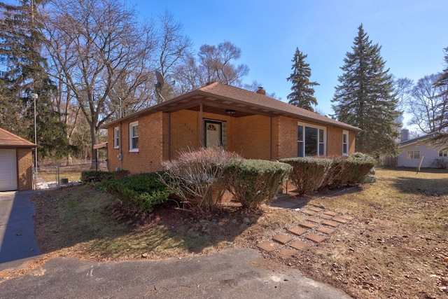 view of property exterior with a gate, fence, a garage, brick siding, and a chimney