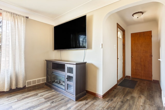 entryway featuring arched walkways, wood finished floors, visible vents, and baseboards