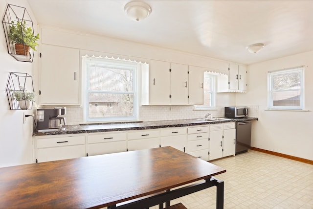 kitchen featuring a sink, tasteful backsplash, dark countertops, stainless steel appliances, and white cabinets