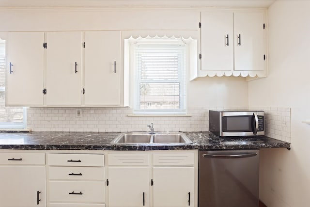 kitchen with a sink, dark stone countertops, white cabinetry, stainless steel appliances, and decorative backsplash