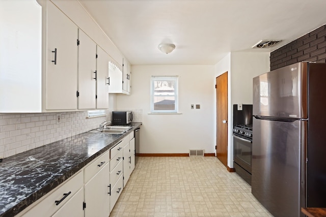 kitchen with a sink, dark countertops, visible vents, and stainless steel appliances