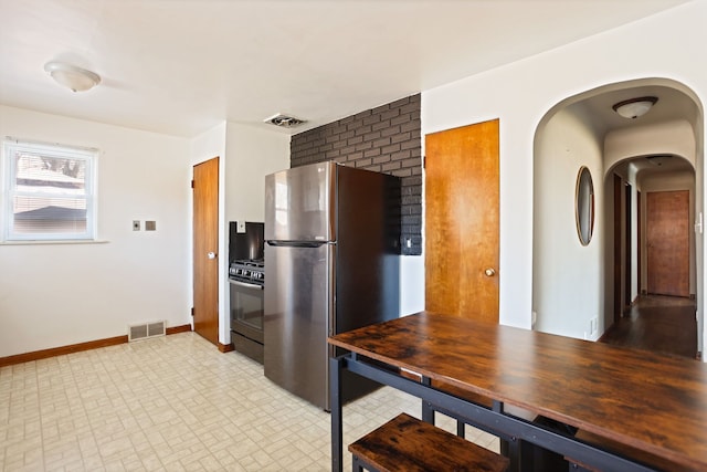 kitchen with visible vents, gas range, freestanding refrigerator, and baseboards