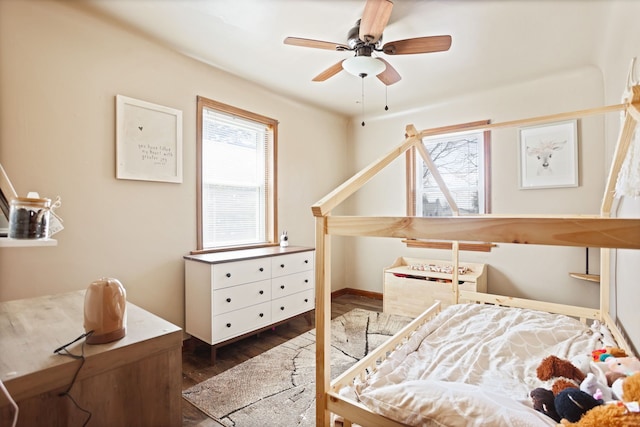 bedroom with multiple windows, dark wood-type flooring, and baseboards