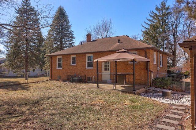 rear view of property featuring brick siding, fence, a chimney, a yard, and a patio