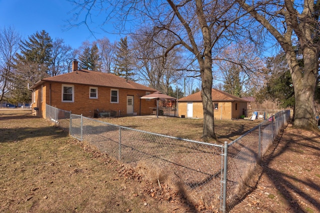 view of property exterior featuring brick siding, fence private yard, a chimney, a yard, and an outbuilding