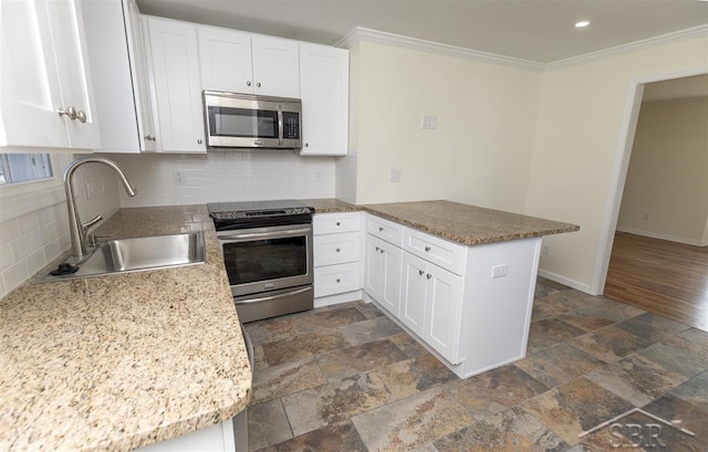 kitchen with crown molding, baseboards, a peninsula, stainless steel appliances, and a sink