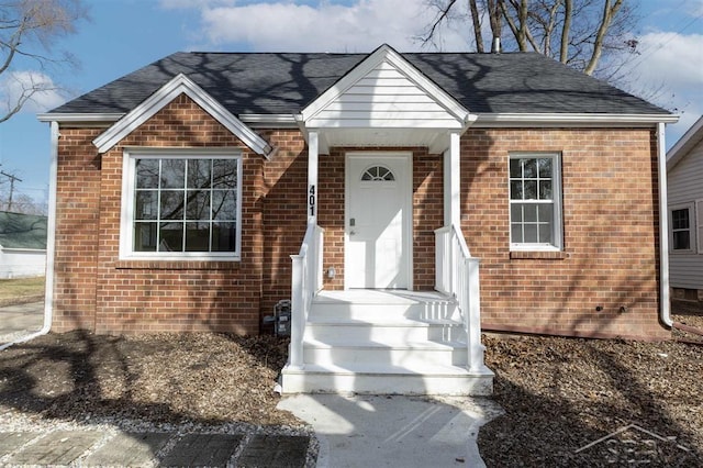 view of front facade featuring brick siding and a shingled roof