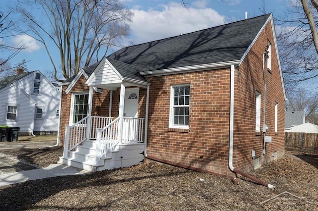 view of front of home featuring brick siding, crawl space, a shingled roof, and fence