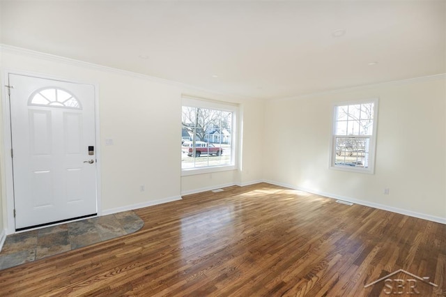 foyer with a wealth of natural light, baseboards, wood finished floors, and crown molding