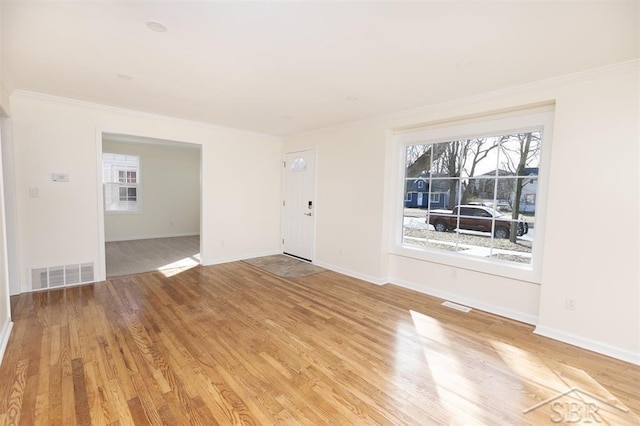 interior space with crown molding, baseboards, visible vents, and light wood finished floors