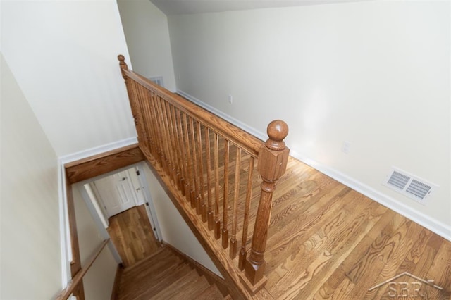 staircase featuring wood finished floors and visible vents