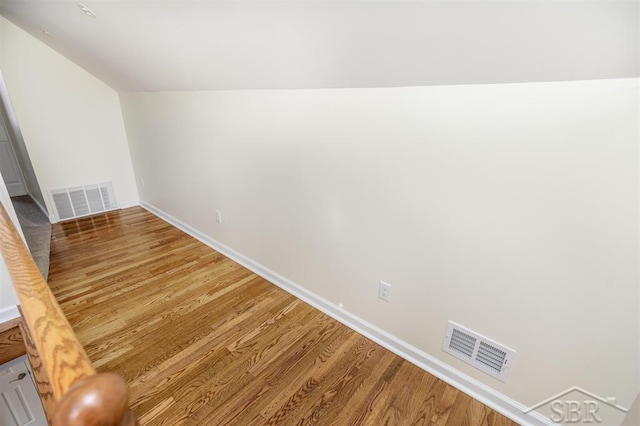 interior space with light wood-type flooring, visible vents, baseboards, and vaulted ceiling