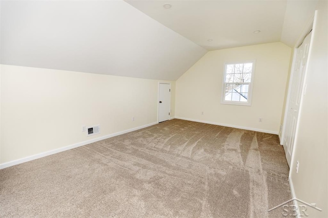 additional living space with visible vents, baseboards, lofted ceiling, and carpet floors