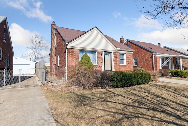 view of front of home with brick siding, fence, a front yard, and a gate