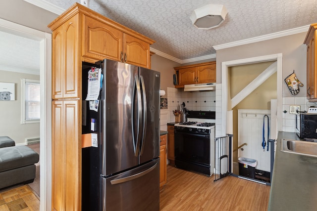 kitchen featuring under cabinet range hood, an ornate ceiling, gas range oven, freestanding refrigerator, and crown molding